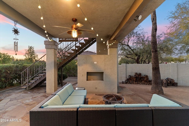 patio terrace at dusk with an outdoor living space with a fireplace and ceiling fan