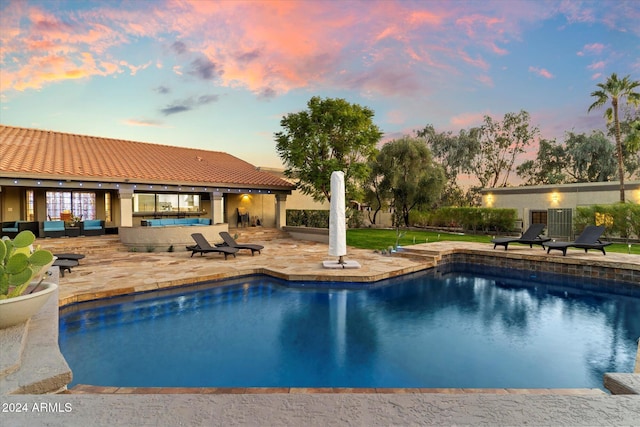 pool at dusk featuring an outdoor hangout area and a patio area