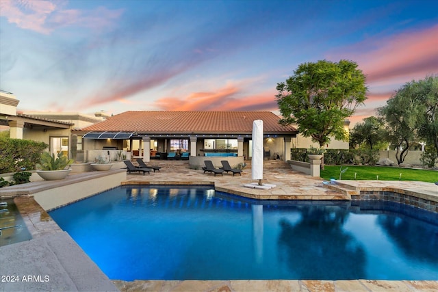 pool at dusk with a patio area