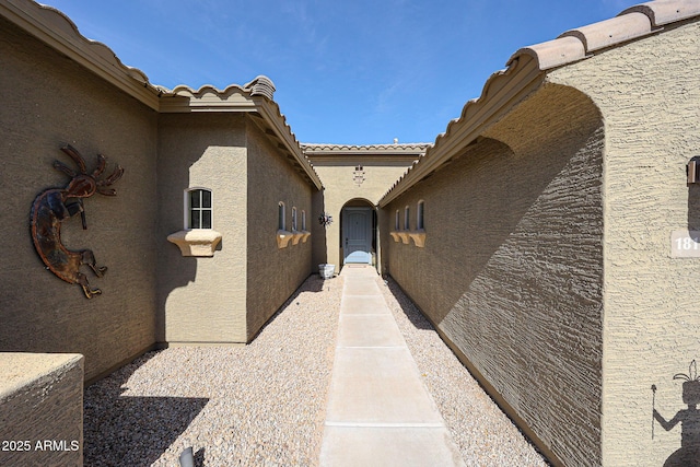 entrance to property with a tile roof and stucco siding