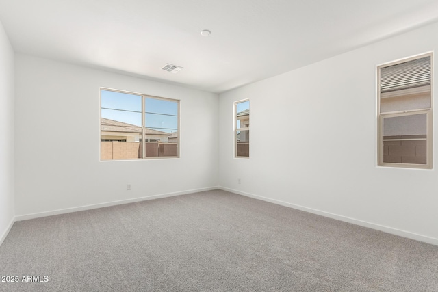 carpeted spare room with visible vents and baseboards