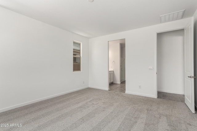 unfurnished bedroom featuring carpet, visible vents, baseboards, and ensuite bathroom