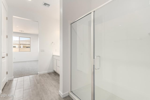 full bathroom featuring a shower stall, vanity, visible vents, wood finished floors, and baseboards
