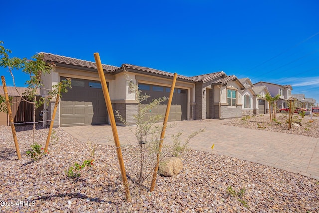 view of front of property featuring a tiled roof, a garage, stucco siding, and driveway