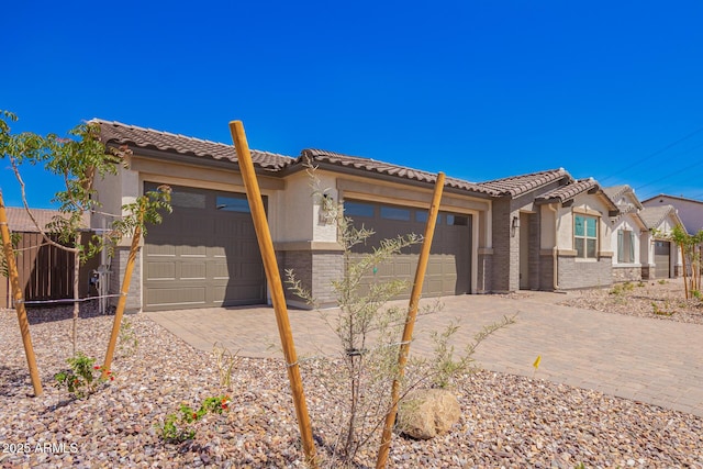 view of front facade featuring a tiled roof, an attached garage, fence, stucco siding, and driveway