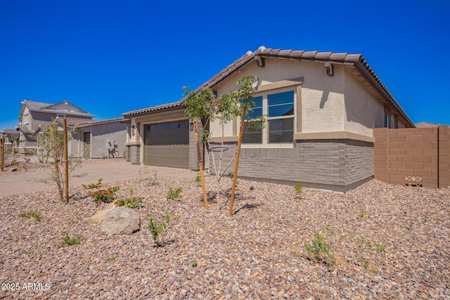 exterior space featuring an attached garage, fence, driveway, and stucco siding