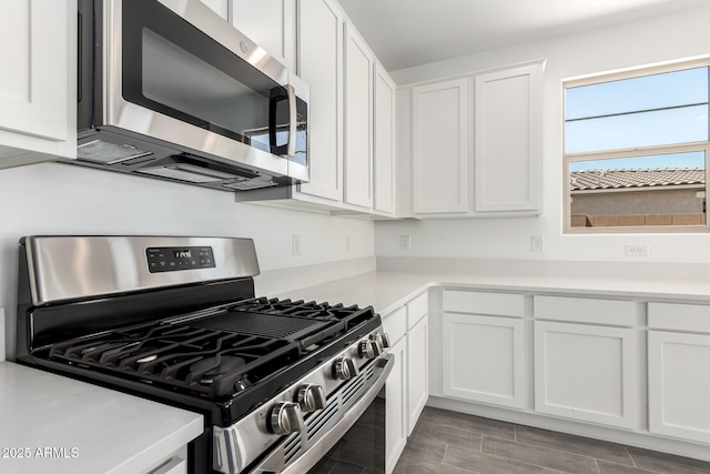 kitchen featuring stainless steel appliances, white cabinets, and light countertops