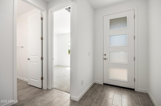foyer entrance featuring visible vents, baseboards, and wood finish floors