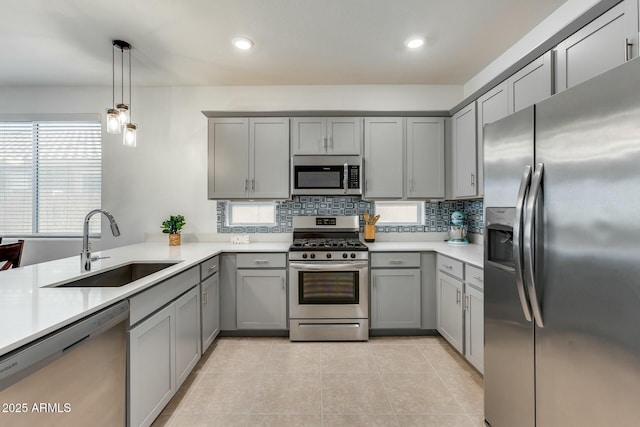 kitchen featuring gray cabinets, decorative light fixtures, sink, and stainless steel appliances