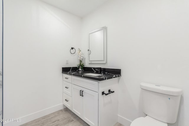 bathroom with hardwood / wood-style floors, vanity, and toilet