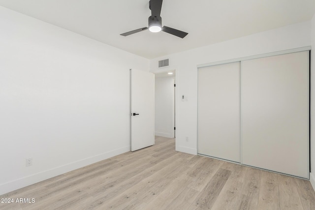 unfurnished bedroom featuring ceiling fan, a closet, and light hardwood / wood-style flooring