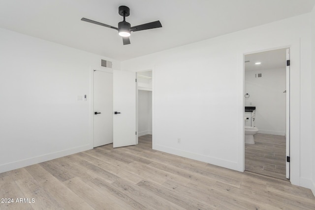 unfurnished bedroom featuring ensuite bathroom, light hardwood / wood-style flooring, and ceiling fan