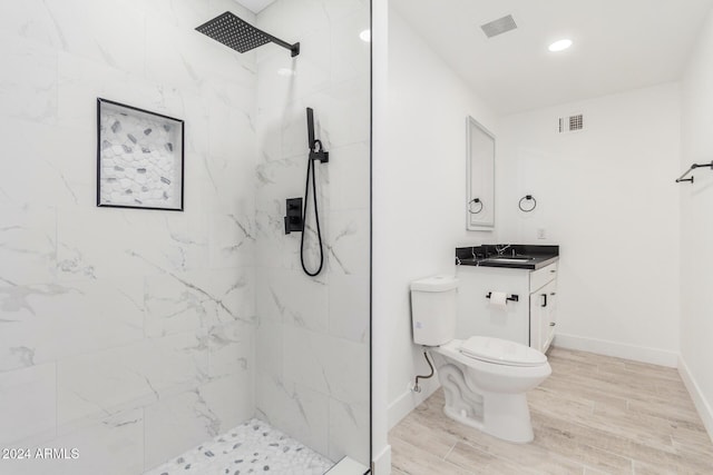 bathroom with vanity, toilet, and a tile shower