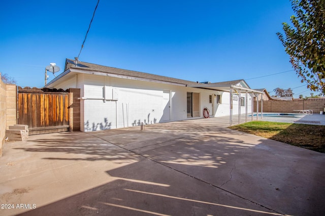 rear view of house featuring a patio and an empty pool