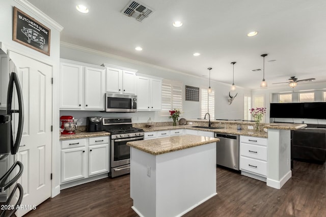 kitchen featuring visible vents, a sink, stainless steel appliances, a peninsula, and white cabinets