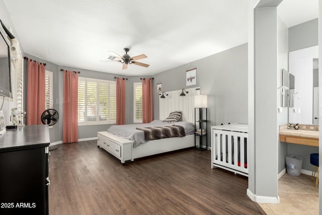 bedroom with ceiling fan, ensuite bathroom, baseboards, and wood finished floors