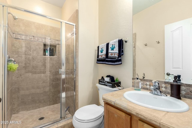 bathroom featuring a shower stall, toilet, and vanity