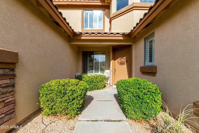 entrance to property with a tiled roof and stucco siding