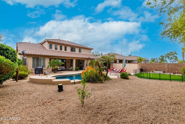 rear view of house with stucco siding, a tiled roof, a patio, and fence