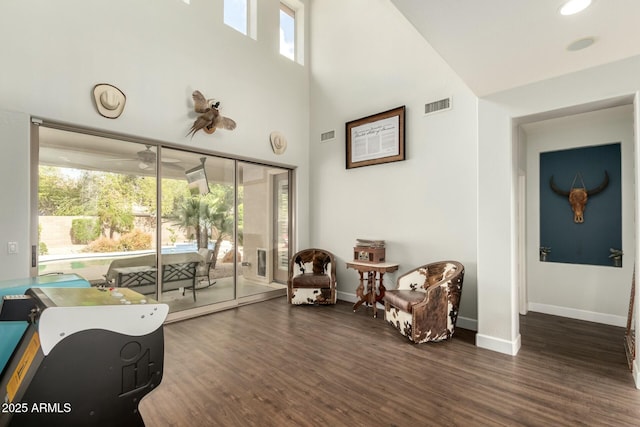 sitting room with visible vents, a high ceiling, baseboards, and wood finished floors