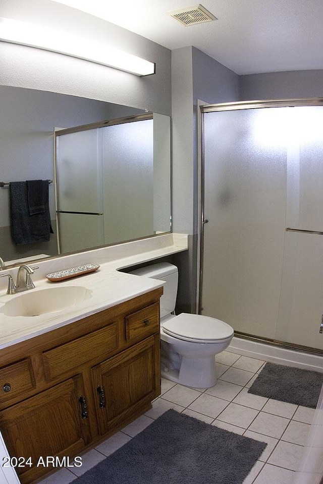 bathroom with tile patterned floors, vanity, toilet, and an enclosed shower