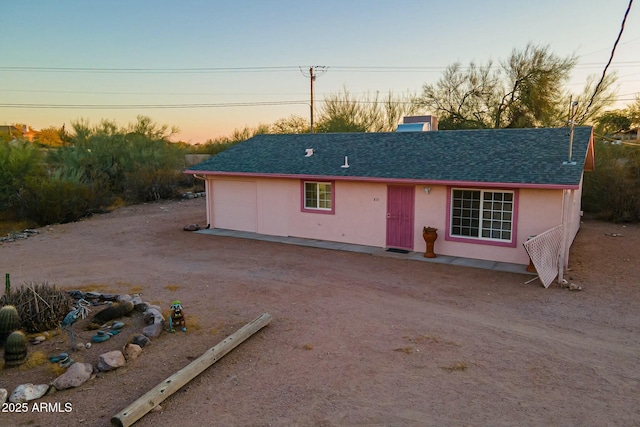 view of front facade featuring roof with shingles, driveway, an attached garage, and stucco siding