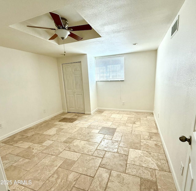 unfurnished bedroom with stone tile flooring, visible vents, a textured ceiling, and baseboards