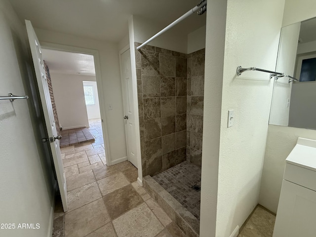 full bathroom with a stall shower, stone tile flooring, and vanity