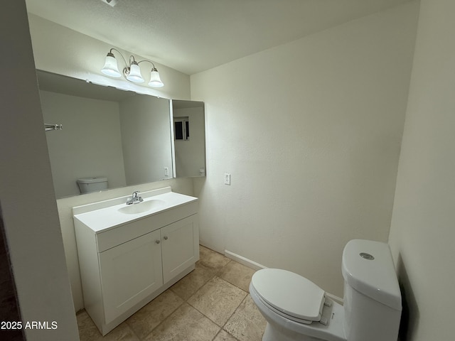 bathroom with toilet, vanity, and baseboards