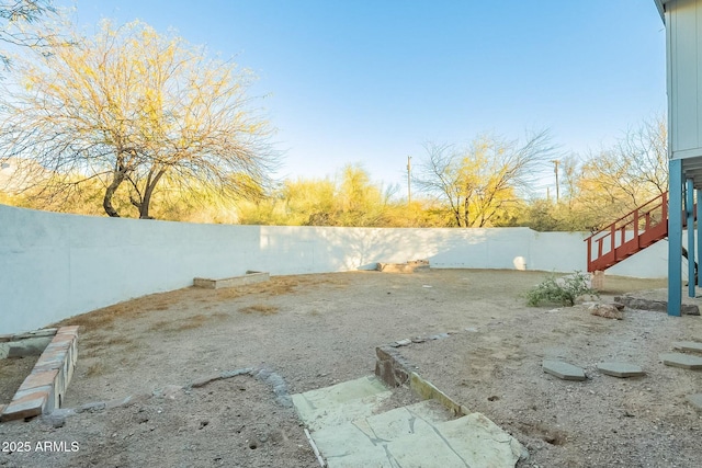 view of yard with a fenced backyard and stairway