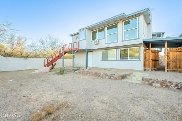 rear view of house featuring stairs and fence