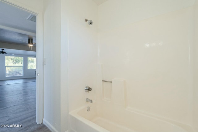 bathroom with wood finished floors, washtub / shower combination, and baseboards