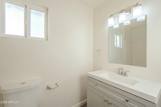 bathroom with baseboards, vanity, and toilet