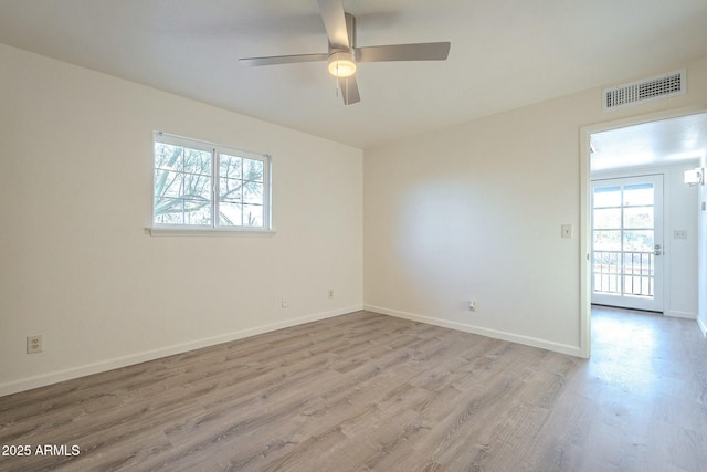 empty room with light wood-style floors, visible vents, baseboards, and a ceiling fan