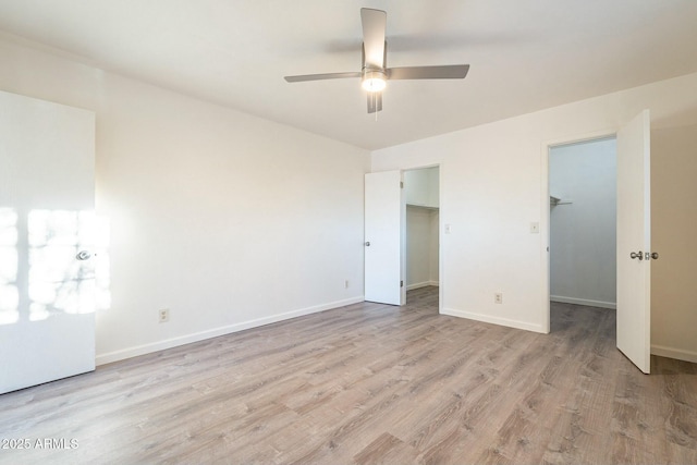 unfurnished bedroom with a spacious closet, light hardwood / wood-style floors, a closet, and ceiling fan