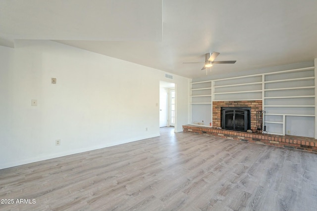 unfurnished living room featuring light wood-style flooring, a fireplace, visible vents, built in features, and a ceiling fan