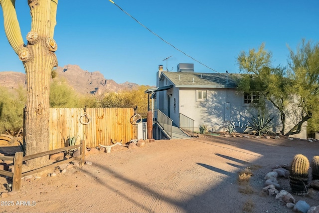 view of home's exterior with stucco siding, a mountain view, and fence