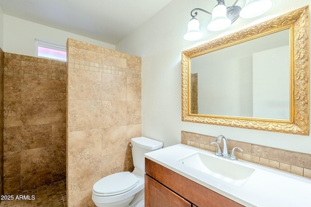 bathroom with tiled shower, toilet, and vanity