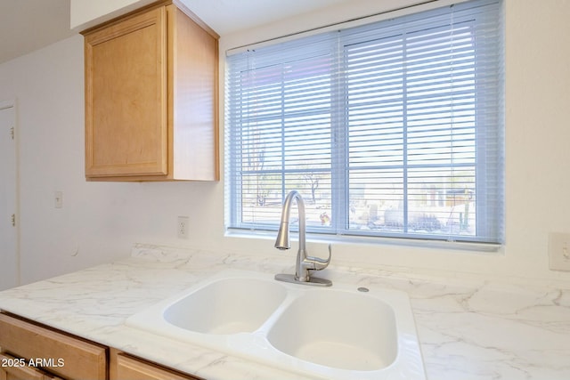 kitchen with sink, light stone countertops, and light brown cabinets