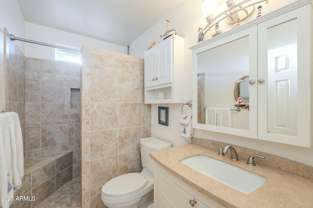 bathroom featuring vanity, toilet, and a tile shower