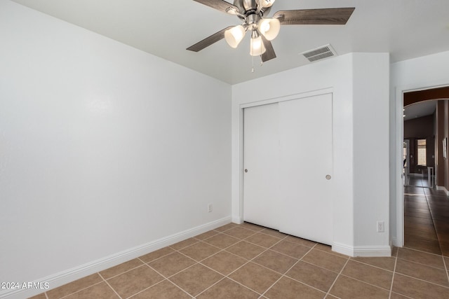 unfurnished bedroom featuring ceiling fan, tile patterned flooring, and a closet