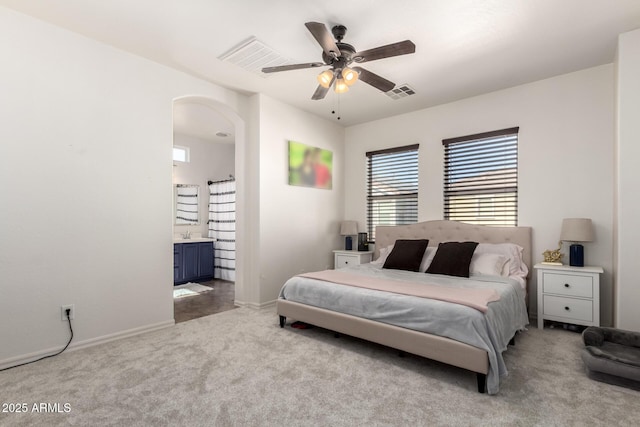 bedroom featuring ensuite bathroom, ceiling fan, and light colored carpet