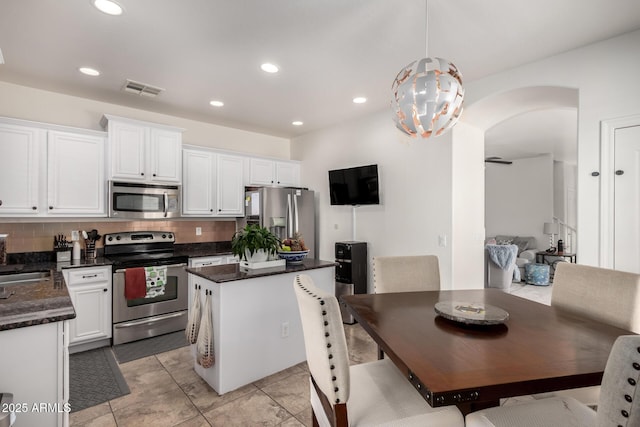 kitchen with tasteful backsplash, stainless steel appliances, light tile patterned floors, white cabinetry, and hanging light fixtures