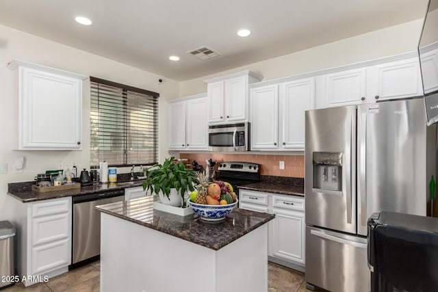 kitchen featuring a center island, dark stone counters, white cabinets, light tile patterned floors, and appliances with stainless steel finishes