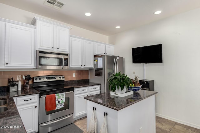 kitchen with tasteful backsplash, white cabinetry, appliances with stainless steel finishes, and dark stone counters