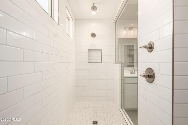 bathroom with tiled shower and sink