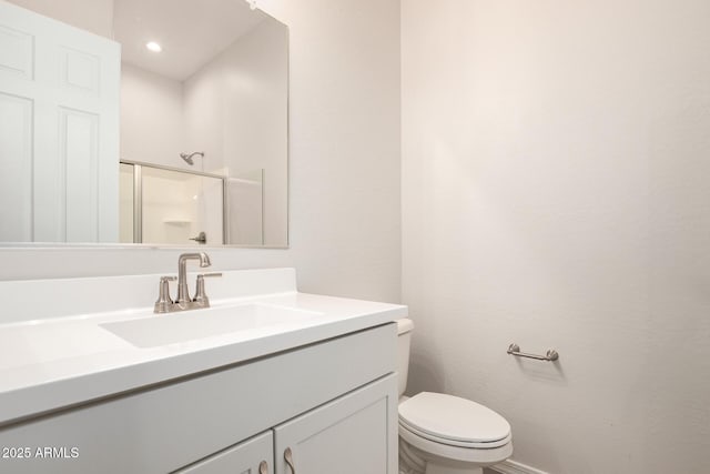 bathroom with a shower with door, vanity, and toilet