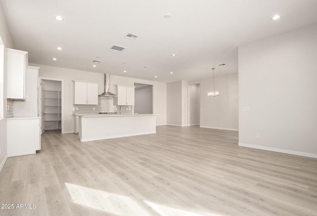 unfurnished living room with a notable chandelier and light wood-type flooring