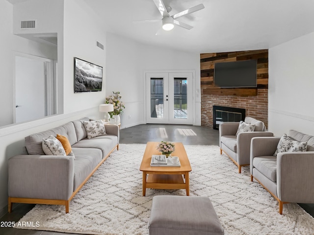 living room with a fireplace, ceiling fan, french doors, and vaulted ceiling