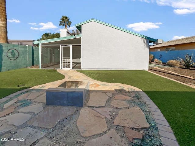 rear view of house featuring a lawn and a sunroom